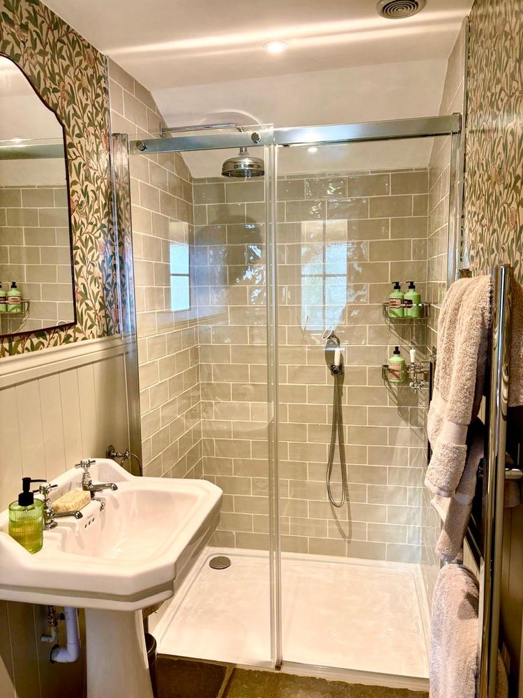 The en‑suite shower room with sage metro tiles and willow‑leaf wallpaper